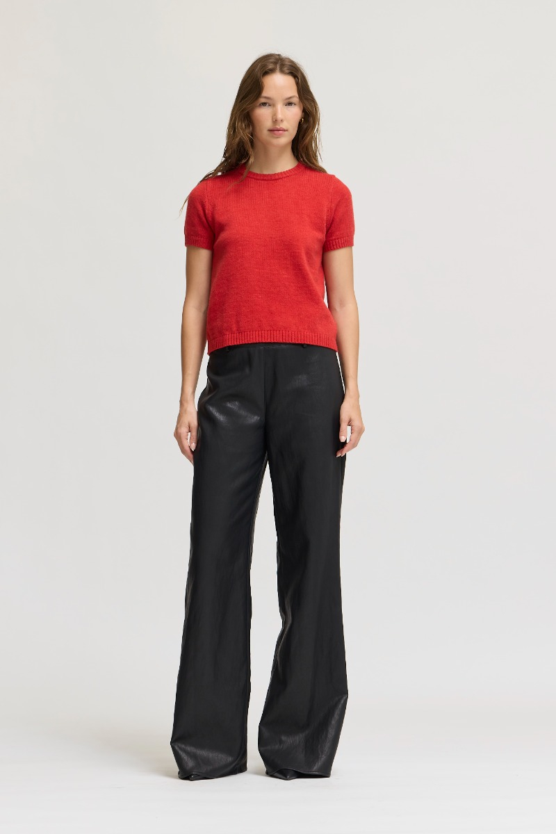 Woman wearing the red Ellie Short Sleeve Knit Top with black wide-leg trousers.