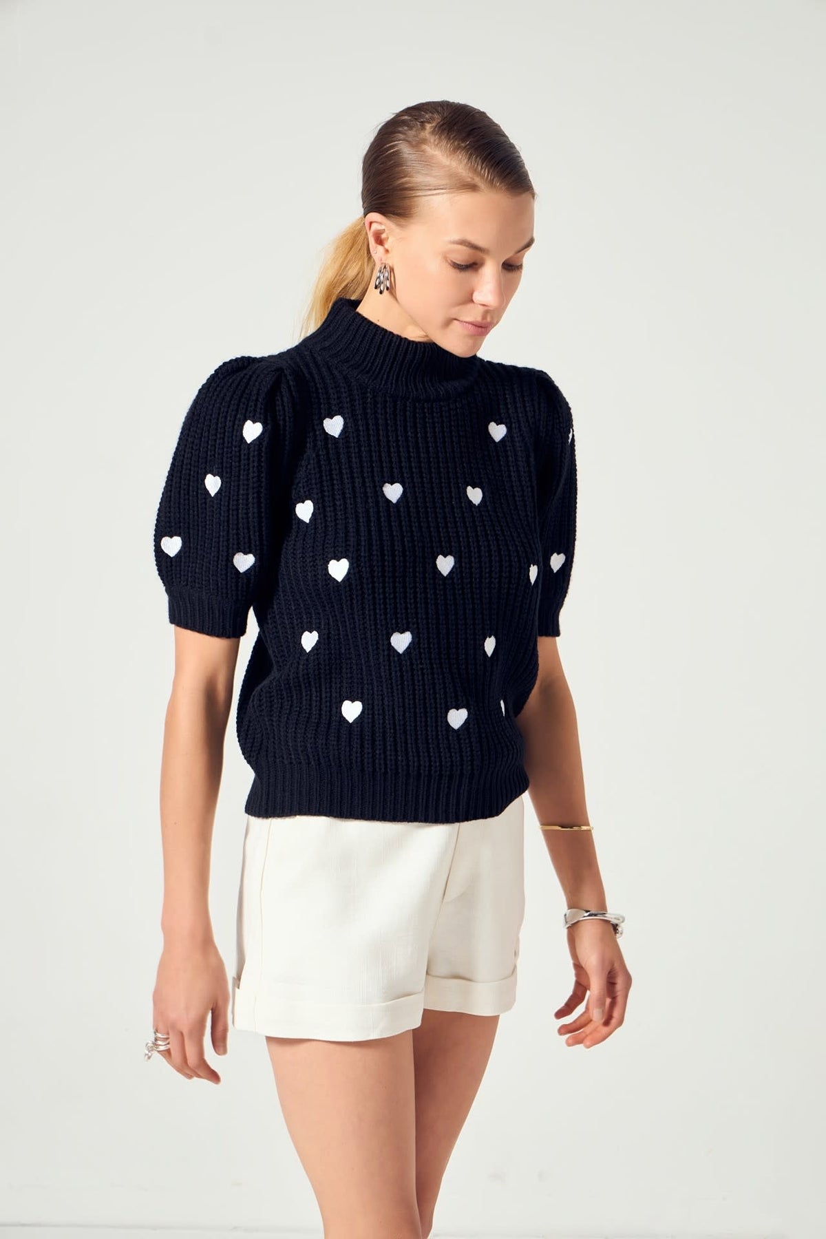 Black acrylic knit sweater with heart embroidery on puffy short sleeves.