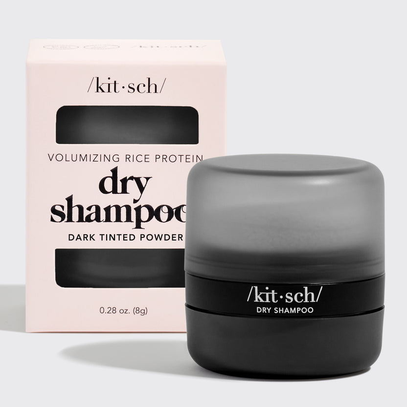 Dark tinted volumizing rice protein dry shampoo powder in a travel-friendly container with built-in puff.