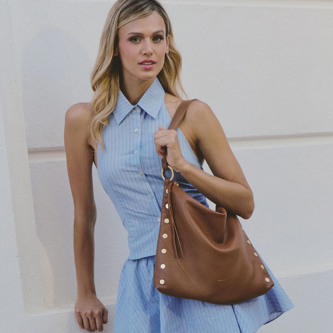 Woman wearing the Kyle Large mahogany pebble leather hobo bag with brushed gold studs.