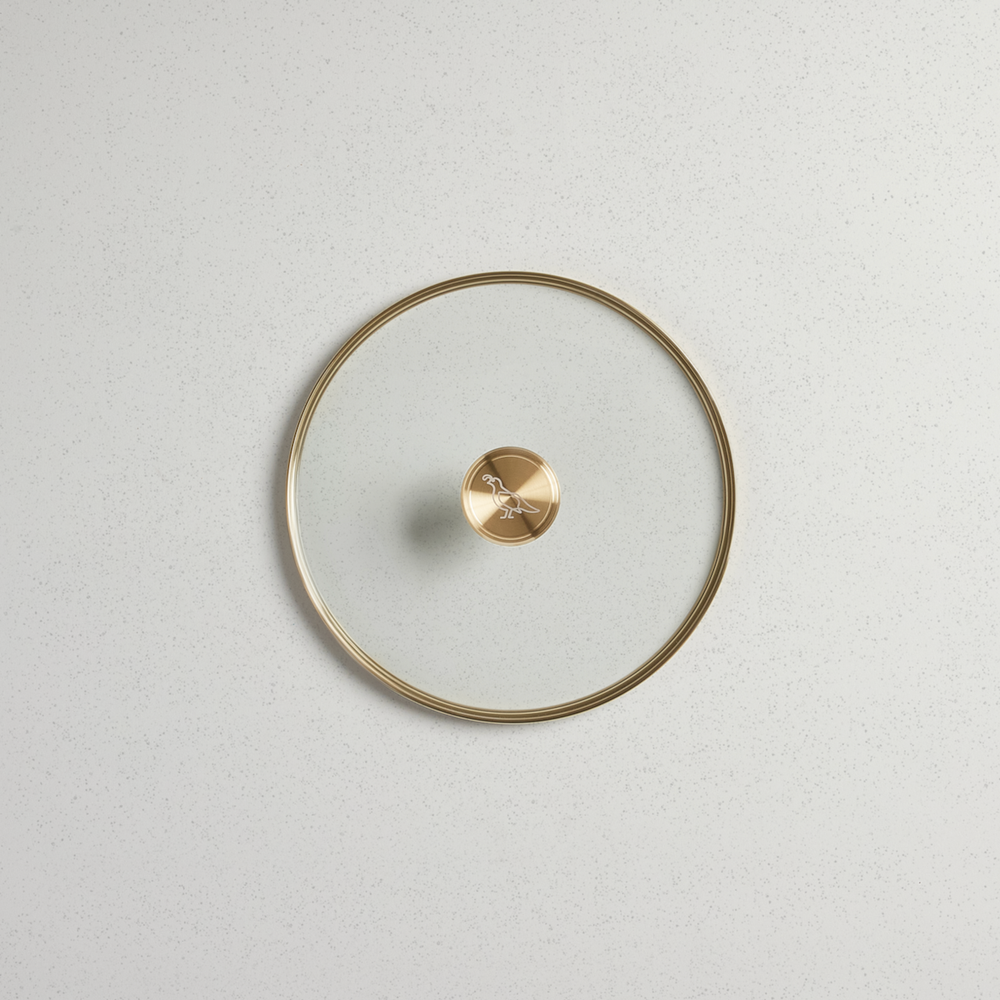 Top view of a 10-inch tempered glass lid with a gold-finished rim and a gold bird-etched knob.