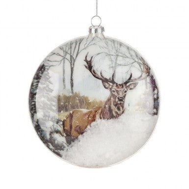 6-inch glass disk ornament featuring a stag in a snowy forest scene with loose snow inside.