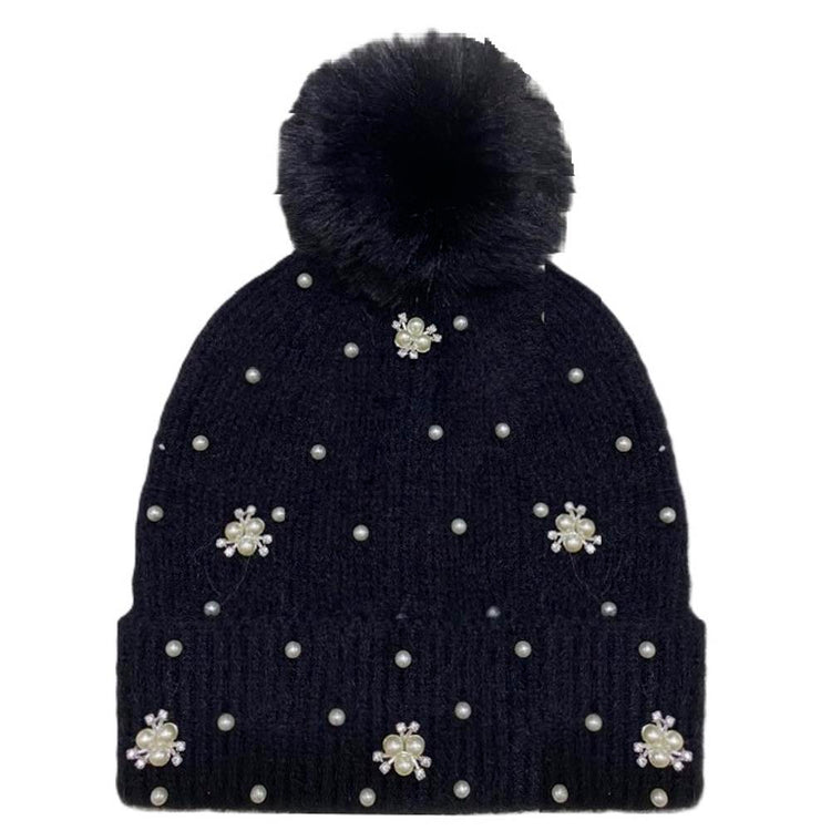 Black knit beanie with a fluffy pom-pom top and delicate pearl studs along the brim.