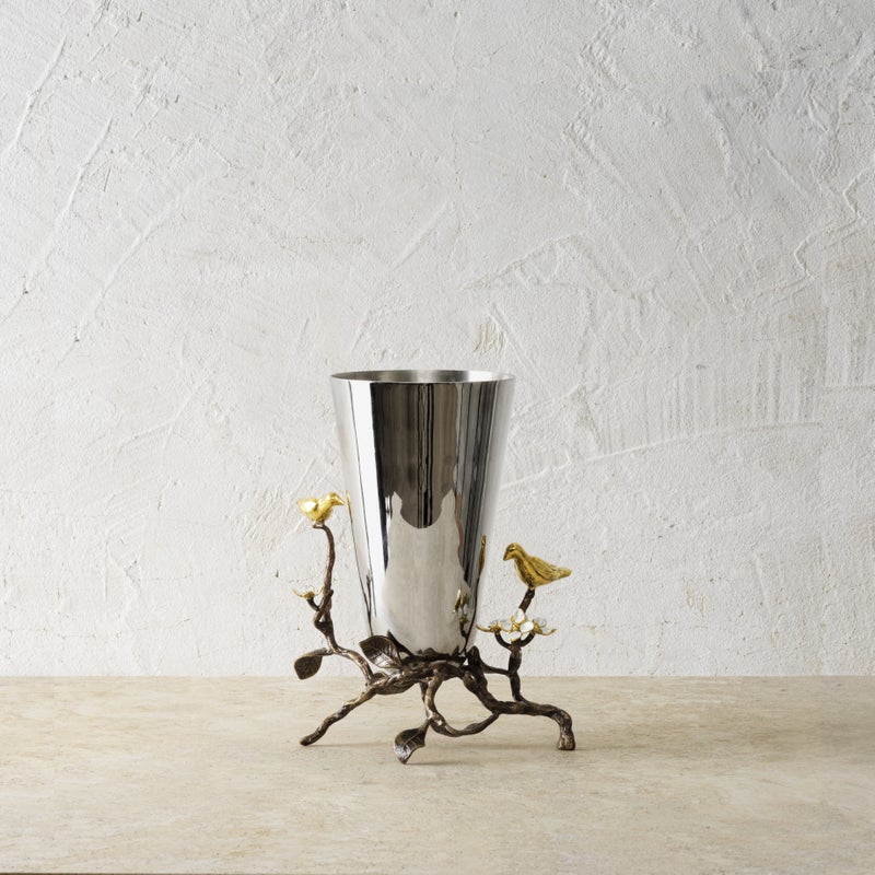 Small stainless steel vase with oxidized brass accents featuring white enamel four-petaled flowers.