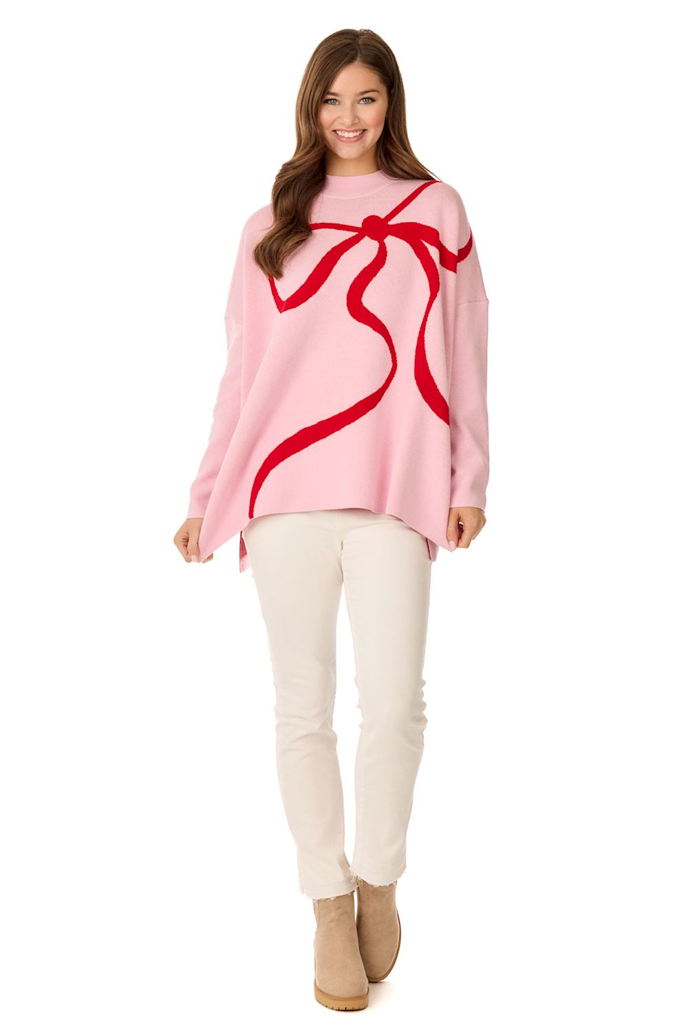 Woman wearing a pink Valentine's Jacquard Sweater with a large red bow design and white pants.
