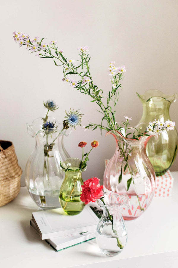 Small vertical fluted glass vase with a hibiscus-inspired pattern in soft tones.