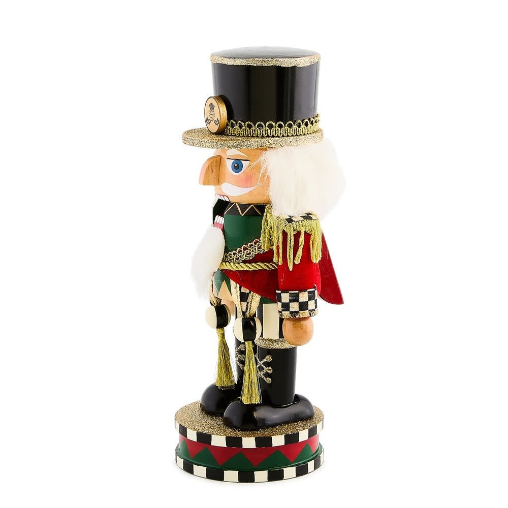Short wooden Highland nutcracker with a red hat and blue uniform standing on a base.