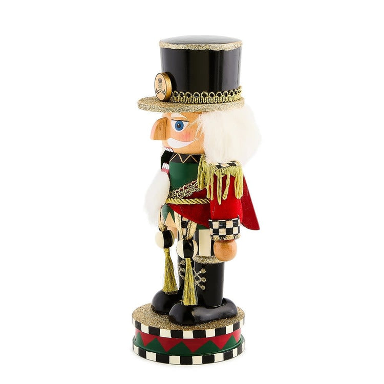 Short wooden Highland nutcracker with a red hat and blue uniform standing on a base.