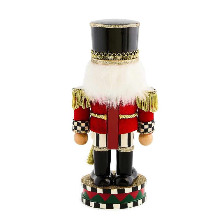 Short wooden Highland nutcracker with red fabric hat and blue uniform standing on a base.