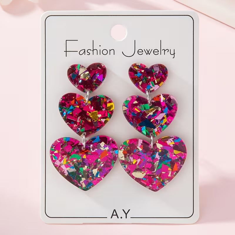 Sparkling heart-shaped sequin earrings with laser-cut acrylic and surgical steel studs.
