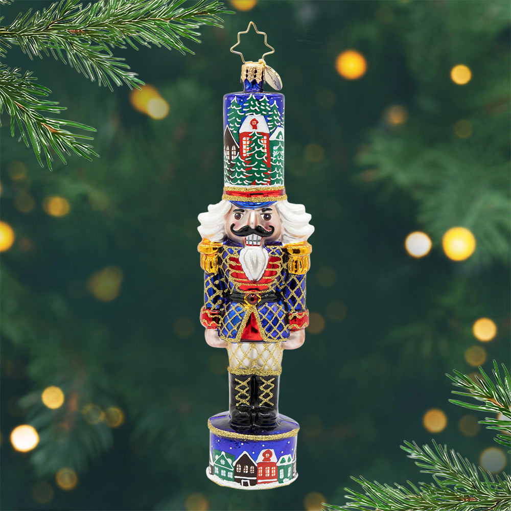 Christmas Sentinel nutcracker ornament in royal blue with snowy village details and gold accents.
