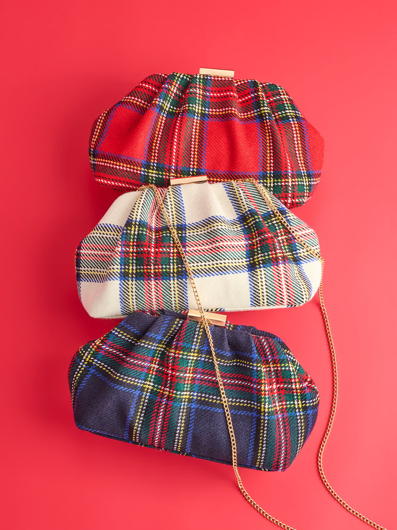 Three Scottie Clutches in red, cream, and navy tartan plaid stacked against a red background.