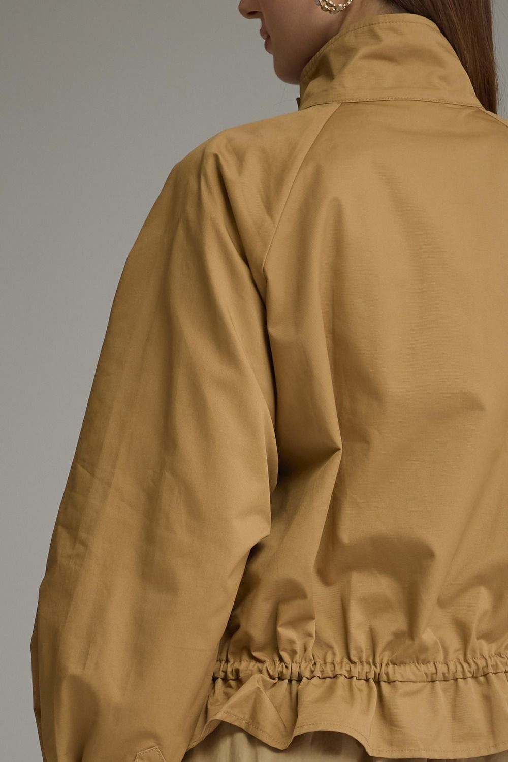 Back view of a tan Andrea Solid Long Sleeve Jacket with a high collar and elasticized hem.