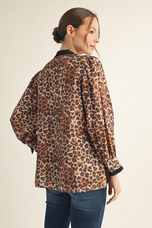 Back view of a woman wearing a leopard print top with a ruffled collar and cuffs.