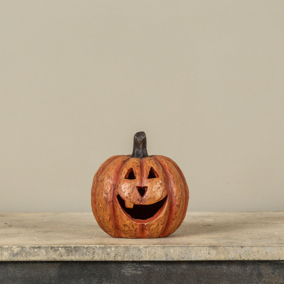 5.5-inch orange mache pumpkin with a large carved smile and triangular eyes on a stone surface.