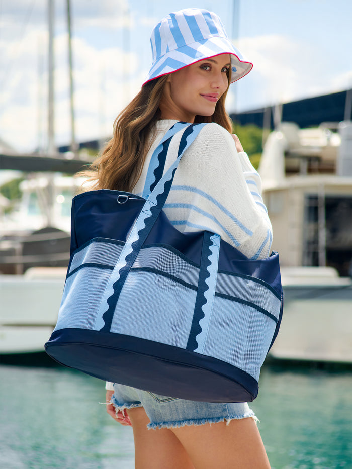 Woman wearing a reversible bucket hat with blue and white stripes and red trim.