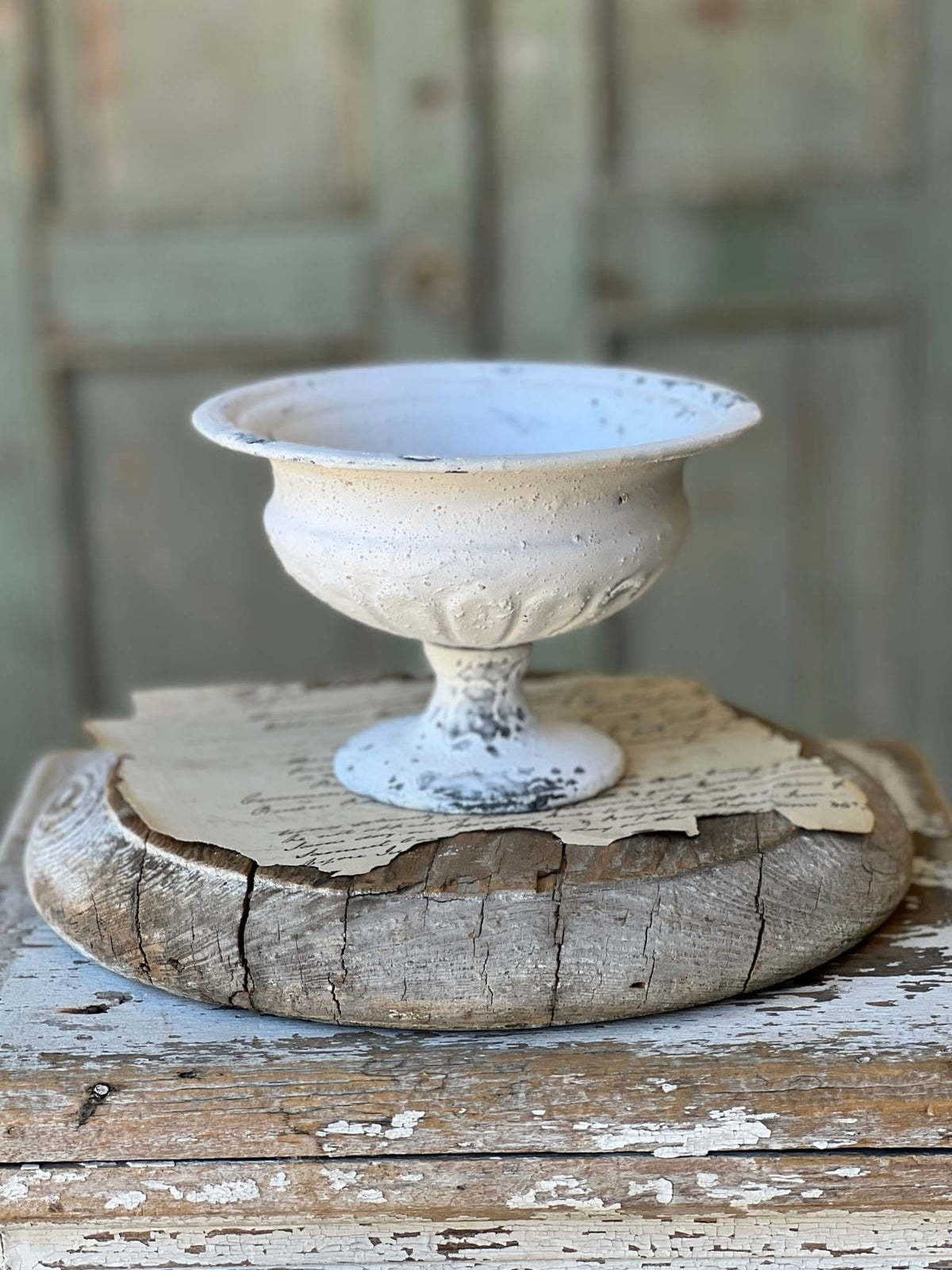 Distressed cream metal urn with a rounded silhouette.