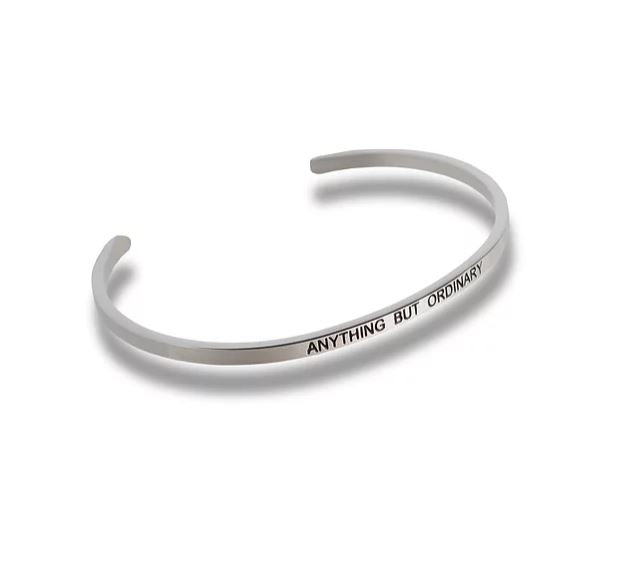 Silver-toned metal cuff bracelet engraved with the text ANYTHING BUT ORDINARY.