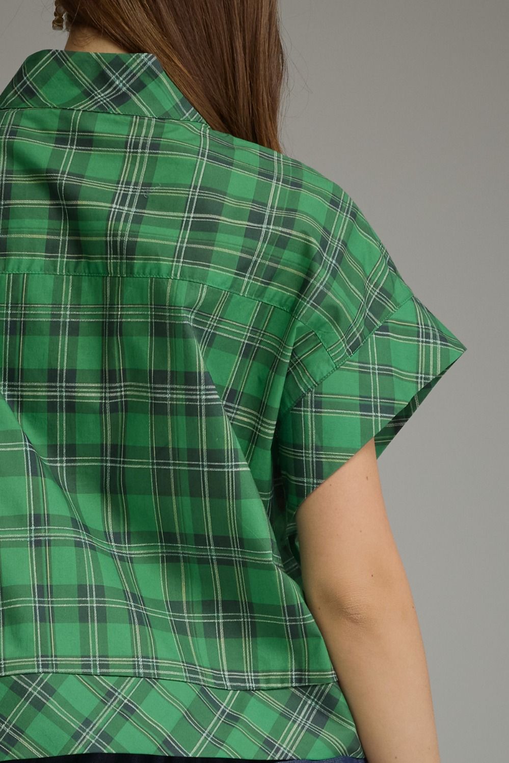 Back view of a green plaid short sleeve top with a folded cuff and button-down collar.