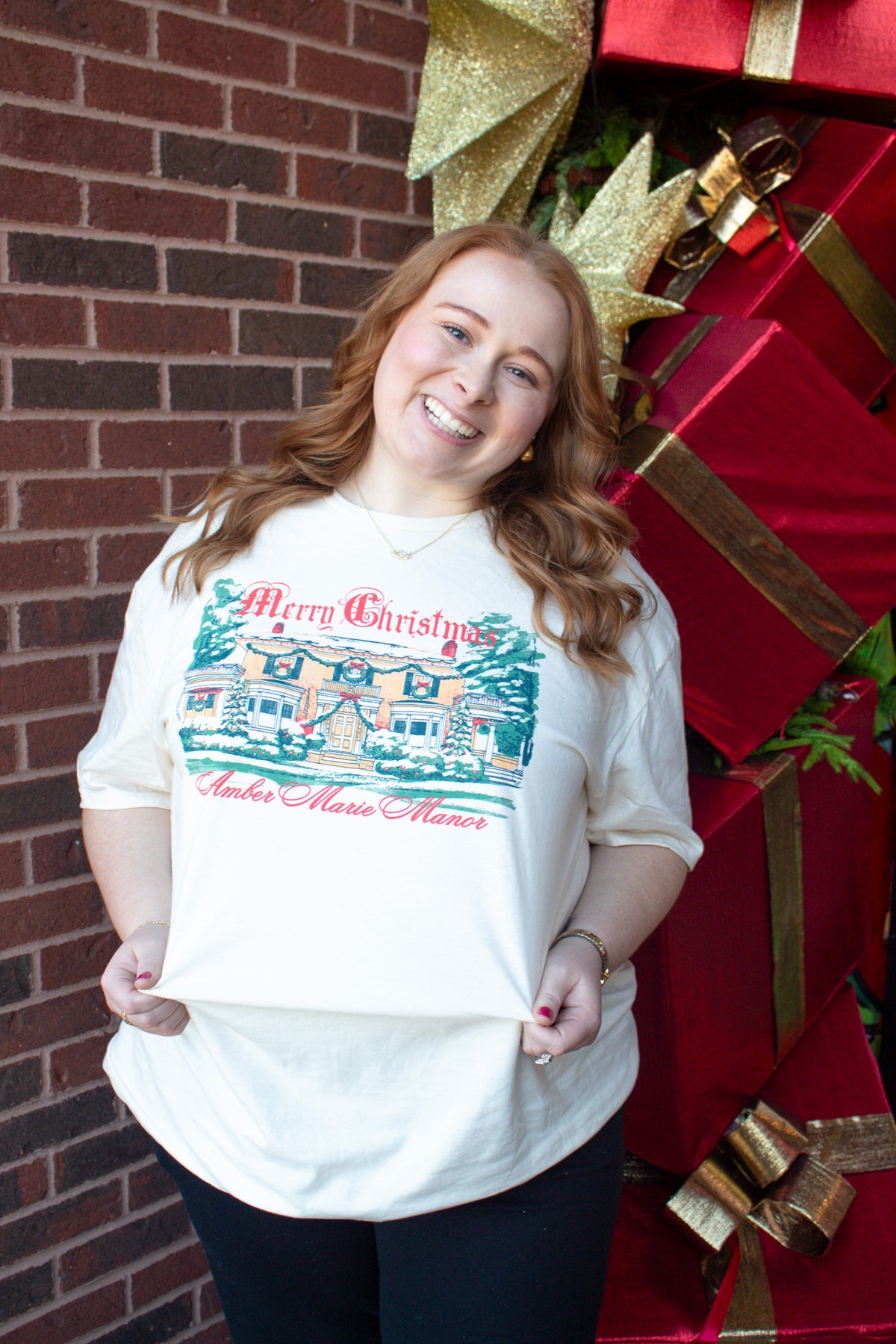 Ivory Christmas shirt featuring an illustration of a decorated manor with text reading Merry Christmas Amber Marie Manor