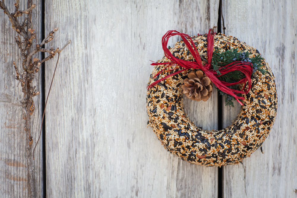 Wildfeast Wreath: a round dried floral arrangement with natural tones accented by a rustic raffia bow.