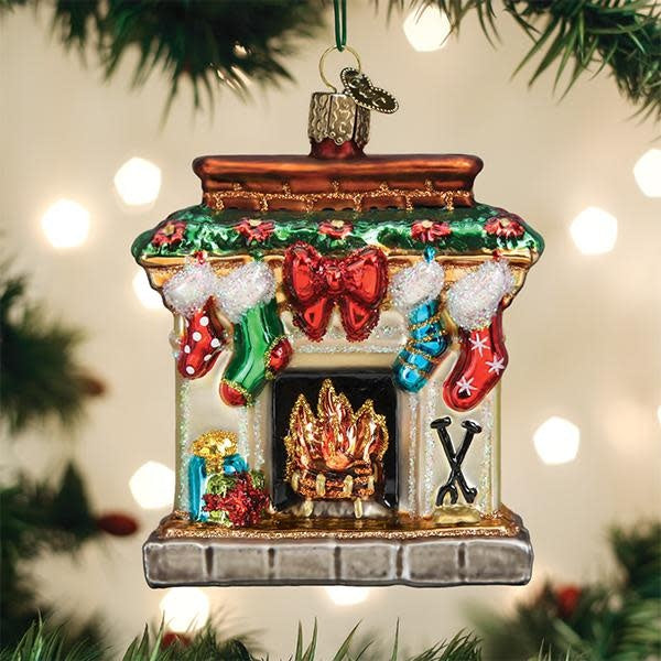 Red glass ornament shaped like a fireplace with glowing yellow flames inside.