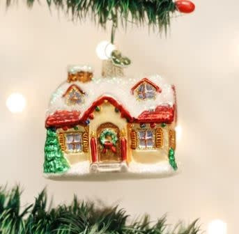 Glass holiday ornament shaped like a quaint cottage with white walls and red roof.