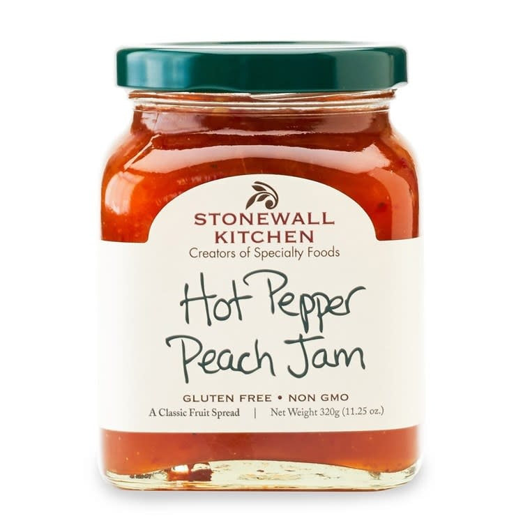 Glass jar containing hot pepper peach jam with a visible red lid.