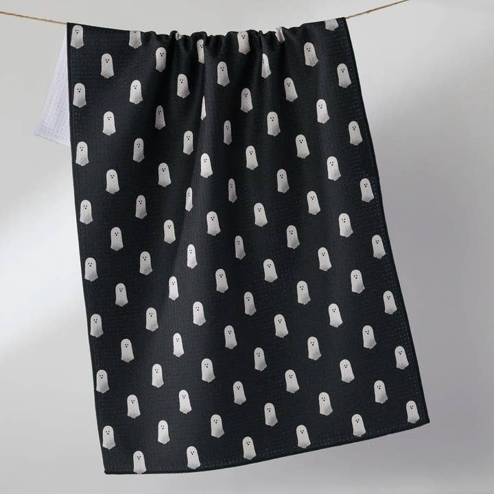 Black waffle weave kitchen tea towel with a white ghost pattern hanging on a clothesline.