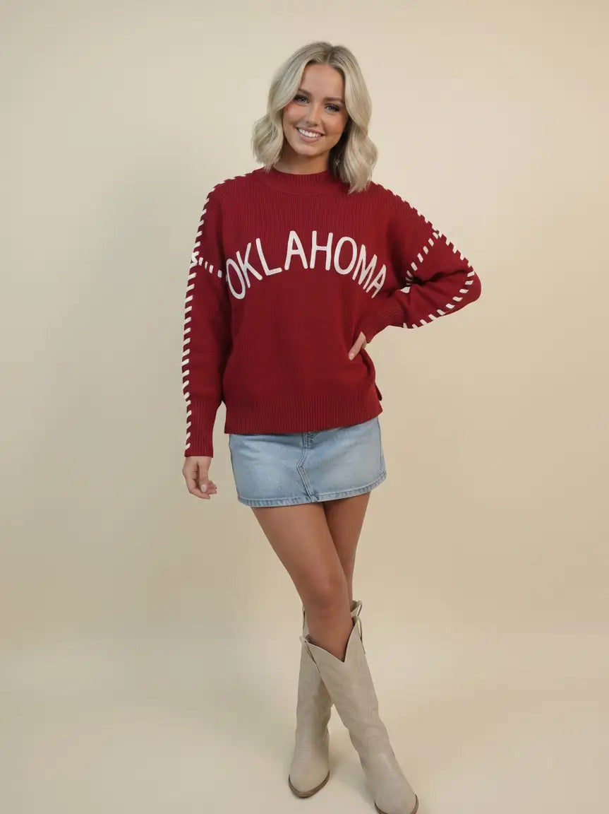 Woman in a red Paisley 'Oklahoma' whip stitch sweater with white lettering and denim skirt.