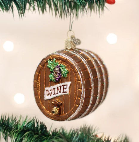 Glass wine barrel Christmas ornament with grape design and 'WINE' label hanging on a tree.