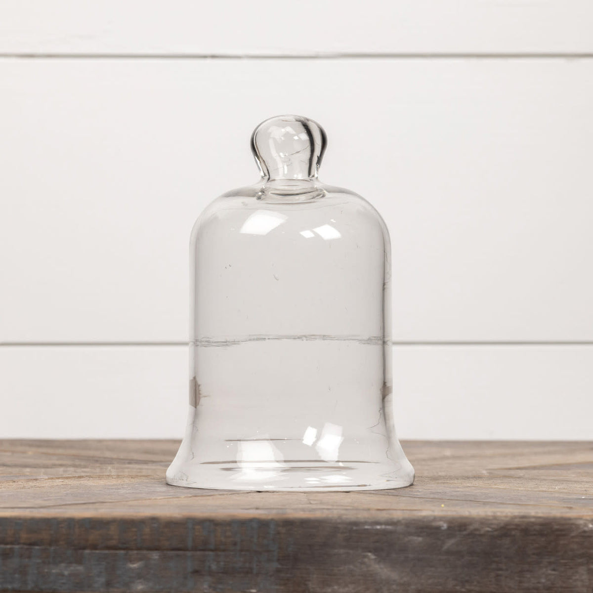 7.5-inch clear glass cloche with a round knob handle on a rustic wooden surface.