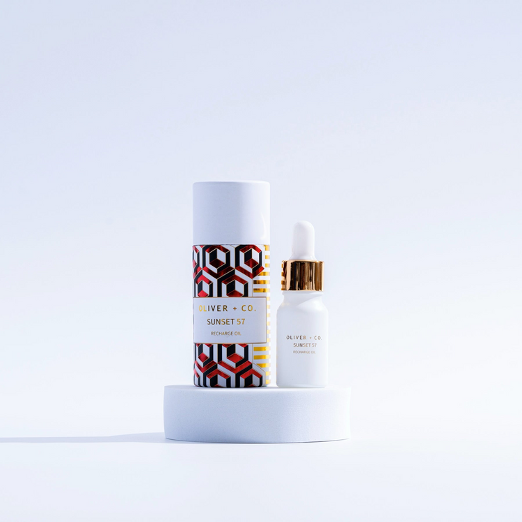 Oliver + Co. Sunset 57 Recharge Oil in a white dropper bottle next to its patterned cylinder box.