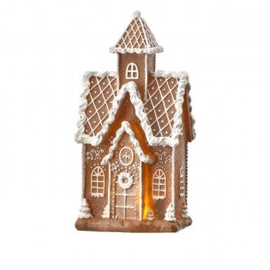 Illuminated gingerbread-style sugar and spice house with white icing details and a steeple.