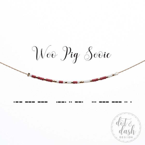 Woo Pig Sooie Morse code necklace with red, white, and gold beads on a thin cord.