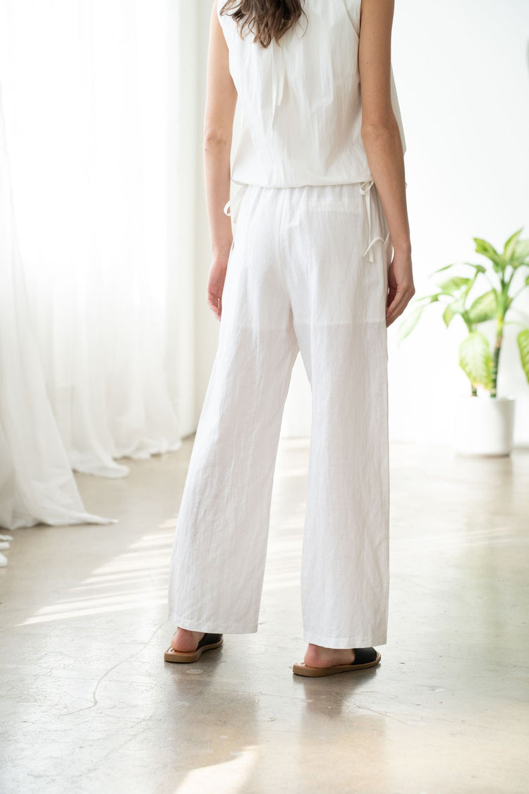 Front view of Laura elastic waist wide-leg linen pants in natural crinkled fabric with side pockets.