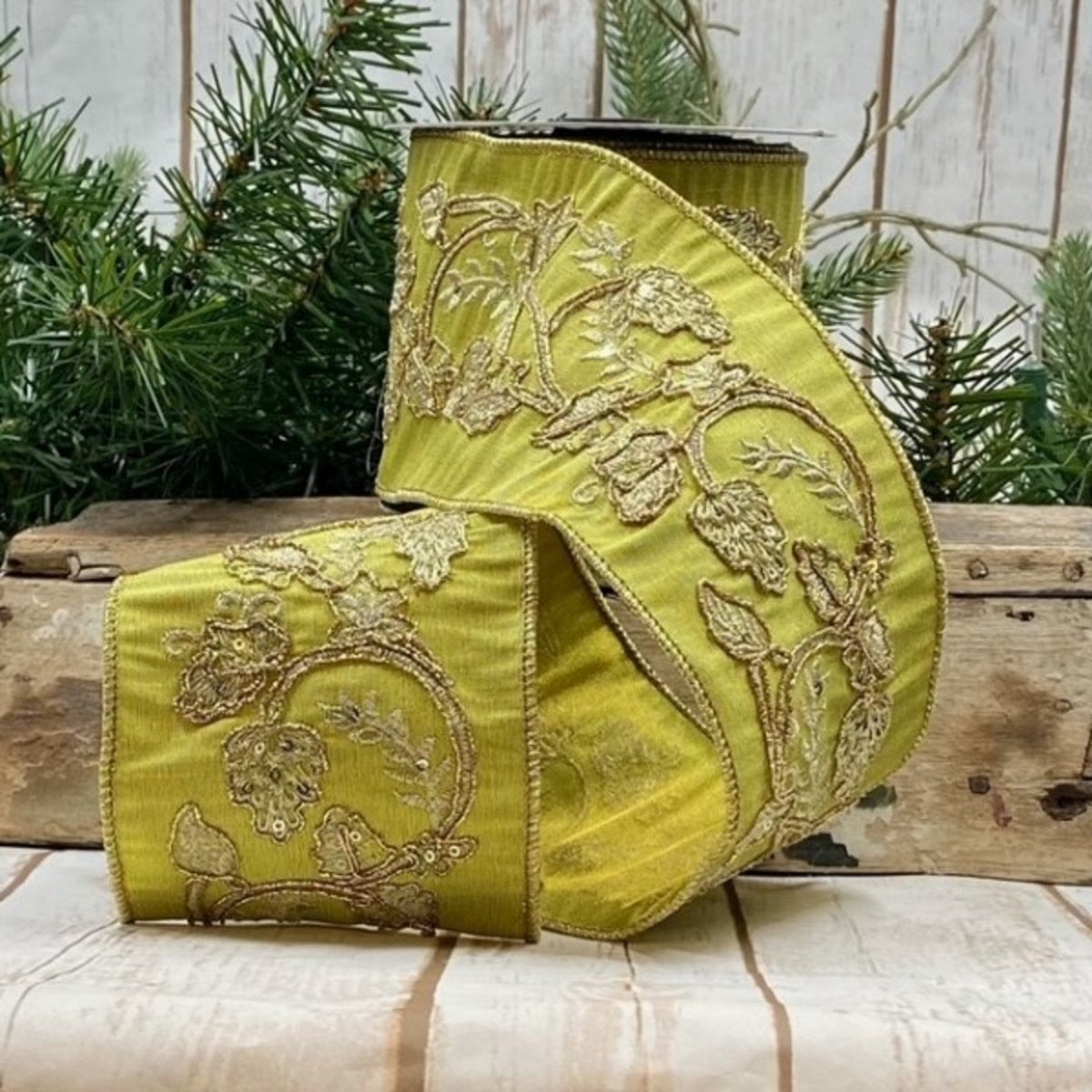 4 inch wide green dupion ribbon with gold embroidered leaf and vine patterns on a spool.