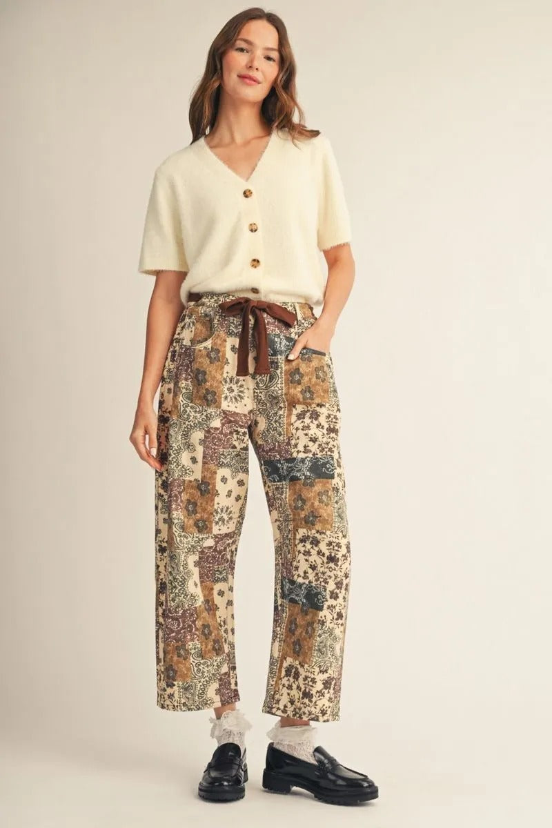 Woman wearing a cream short-sleeved fuzzy button-down cardigan with patterned patchwork pants.