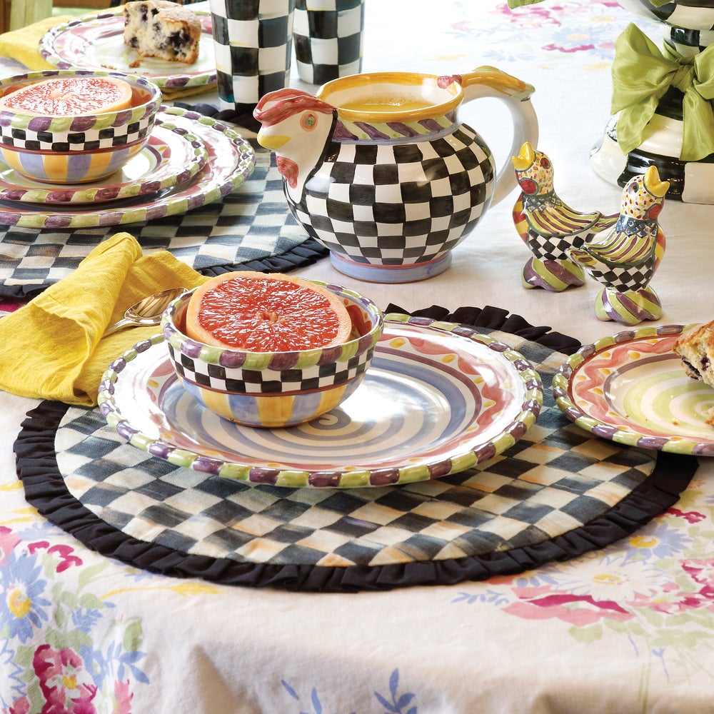 Courtly Check Round Placemat on a floral tablecloth with colorful patterned dishes and a pitcher.