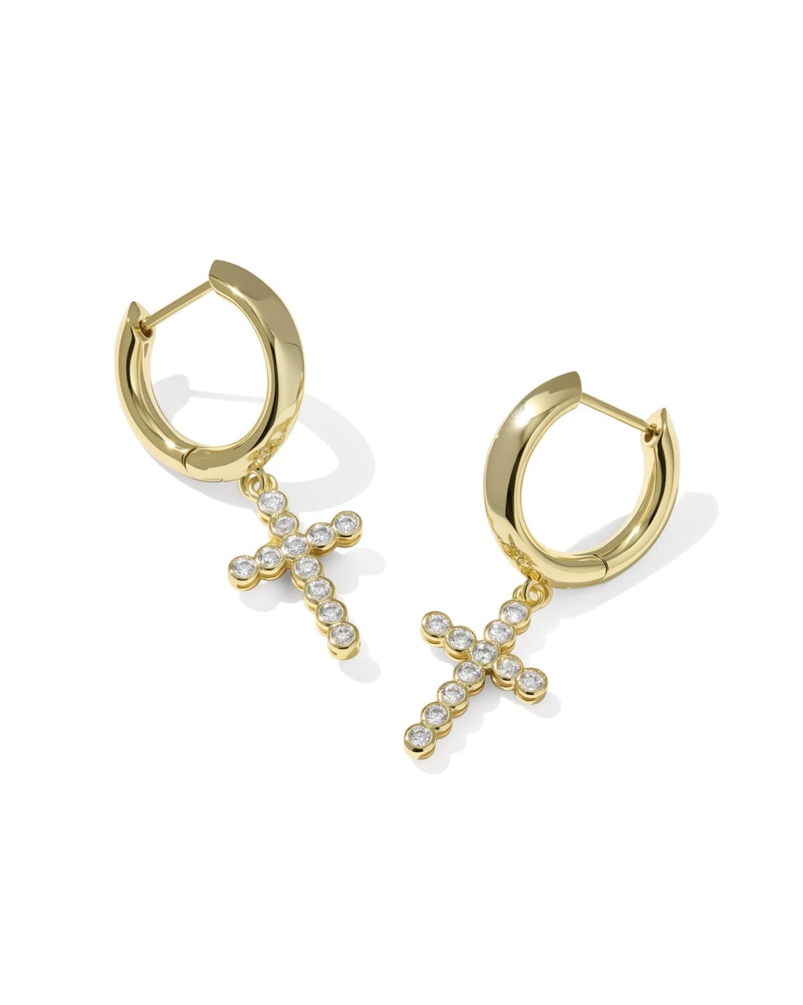 White cubic zirconia cross charm on a metallic huggie hoop earring