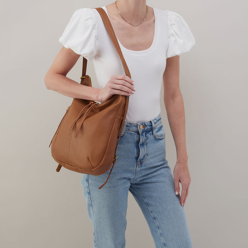 Woman wearing the Merrin Convertible Backpack in Warm Honey leather as a shoulder bag.