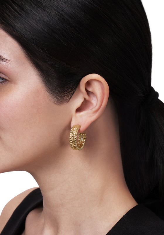 A person wearing a 1-inch diameter 18K gold plated brass braided hoop earring.