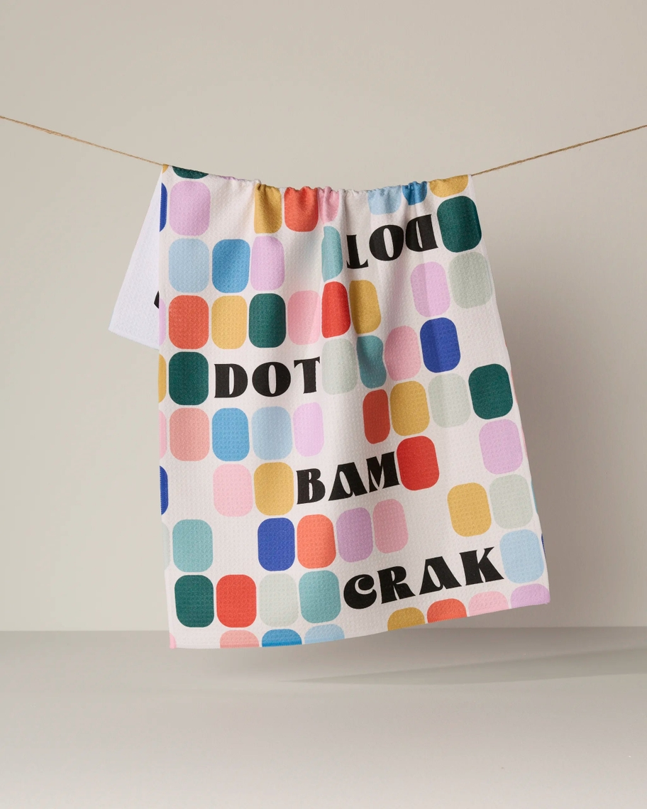 Everyday Tea Towel with colorful rounded rectangles and bold black text hanging on a twine line.