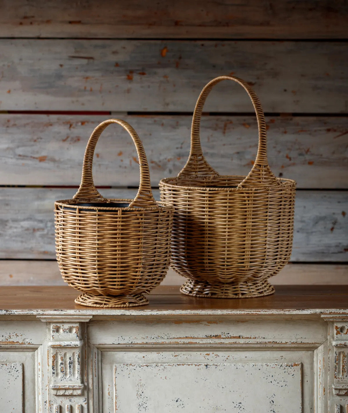Two woven poly baskets with handles, one smaller than the other, sit on a wooden surface.