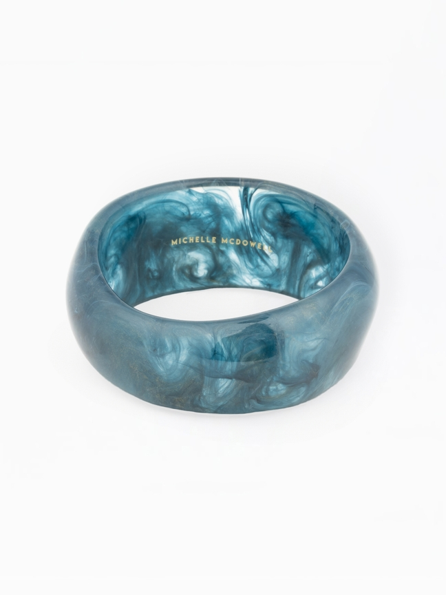 Sally Bangle, a thick blue marbled resin bracelet with gold Michelle McDowell branding inside.