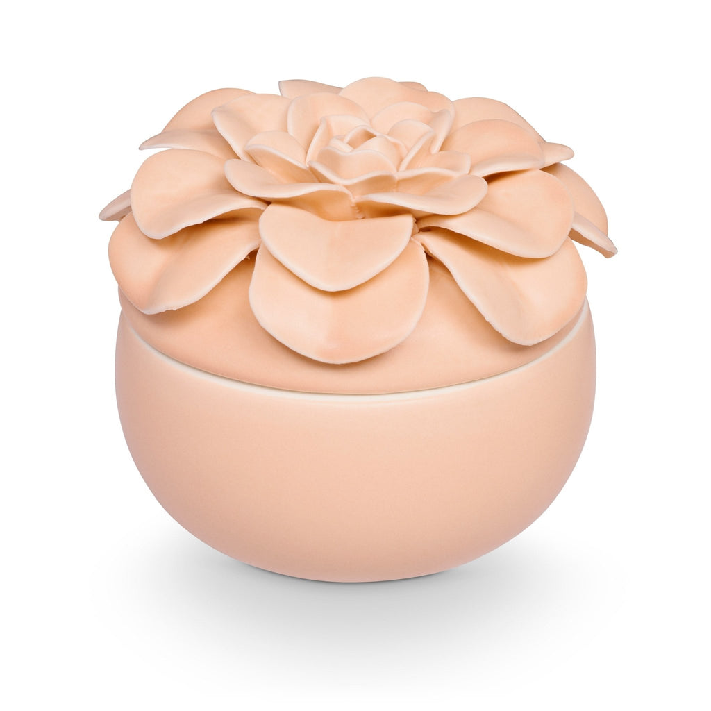 Round peach ceramic candle jar topped with a large, multi-layered sculpted ceramic flower lid.