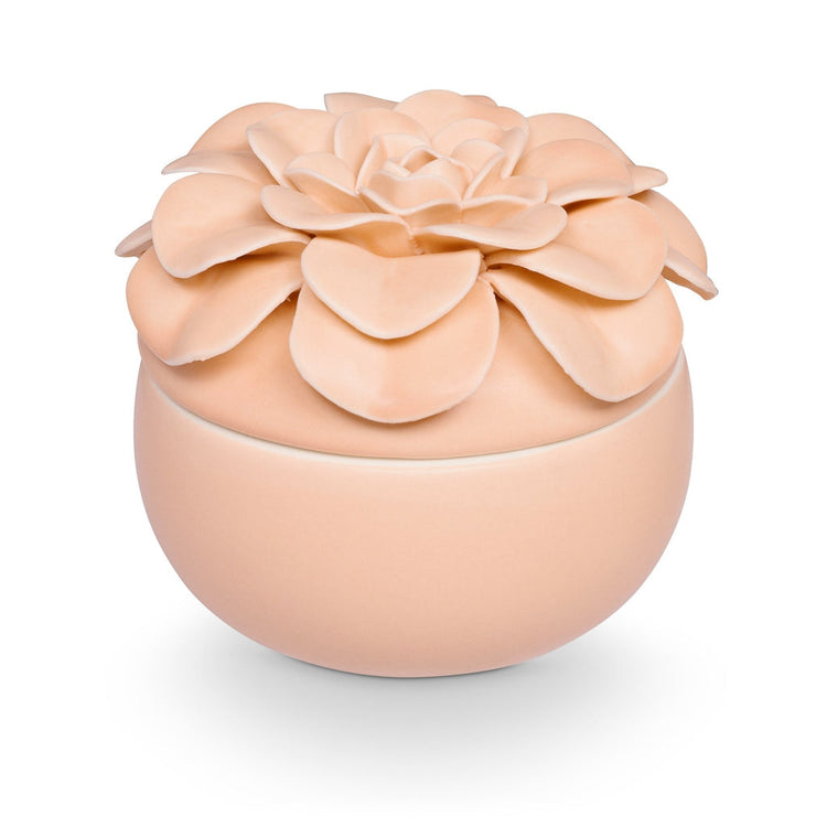 Round peach ceramic candle jar topped with a large, multi-layered sculpted ceramic flower lid.