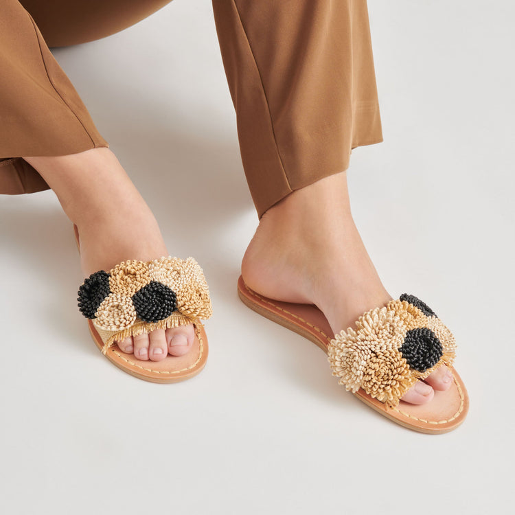 Person wearing Danela Sandals with raffia pom-pom straps in beige and black.