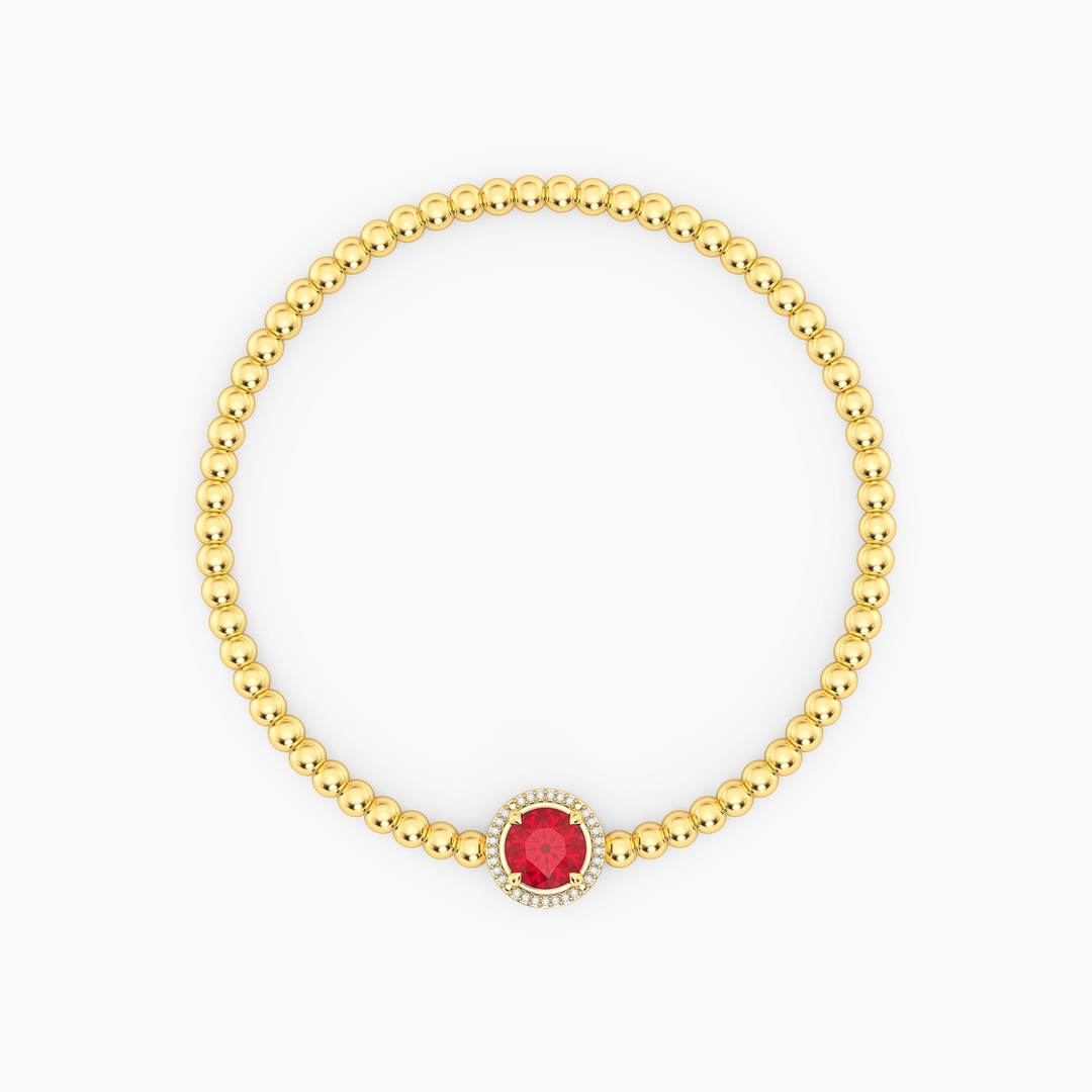 Gold beaded bracelet with a round red center gemstone and a halo of small diamonds.