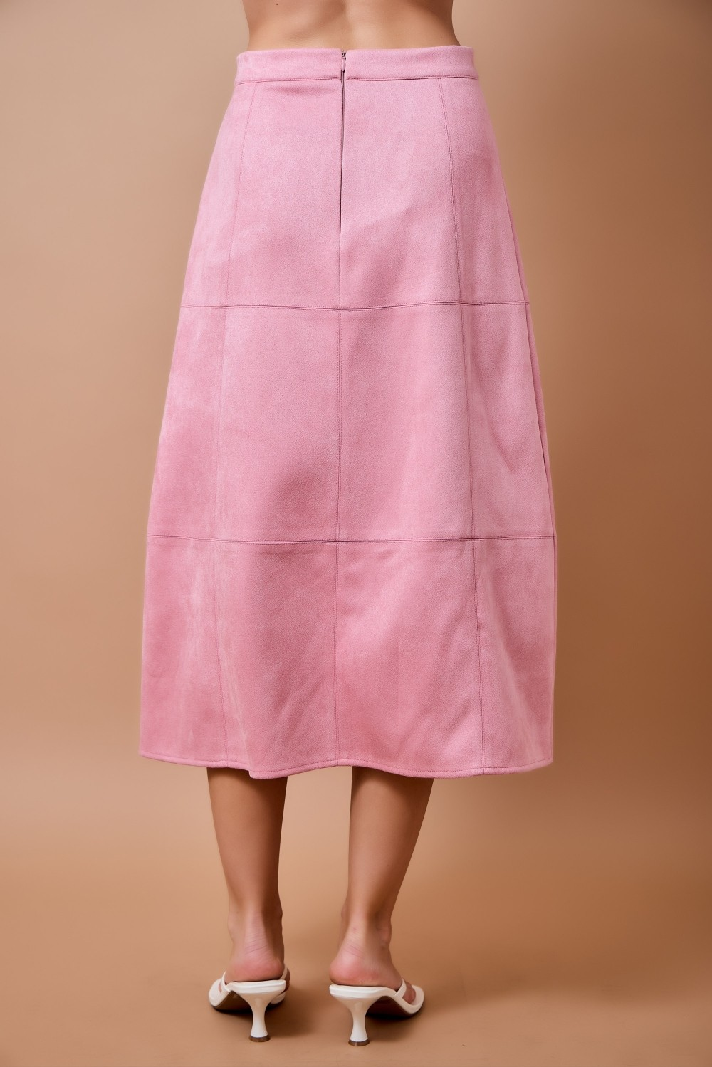 Back view of a pink high-waisted suede A-line midi skirt with panel seam detailing.
